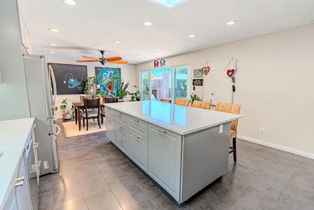 a large kitchen with stainless steel appliances a white stove top oven a dining table and chairs with wooden floor