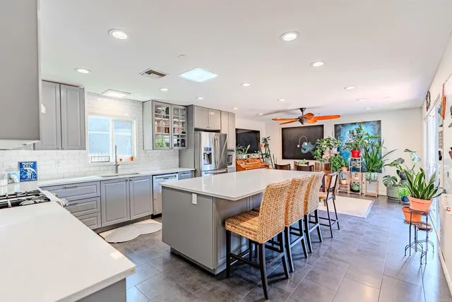 a kitchen with stainless steel appliances kitchen island granite countertop a dining table chairs and white cabinets