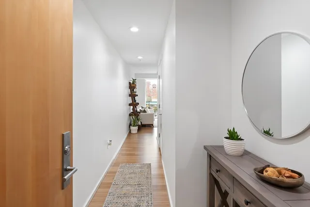 a view of a hallway with wooden floor and a bathroom