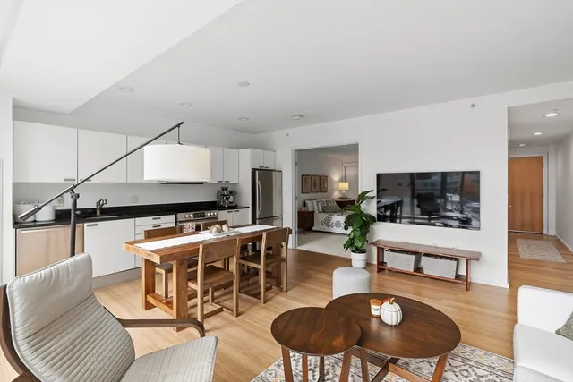 a living room with furniture potted plant and kitchen view