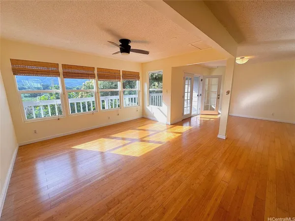 a view of an empty room with wooden floor and a window