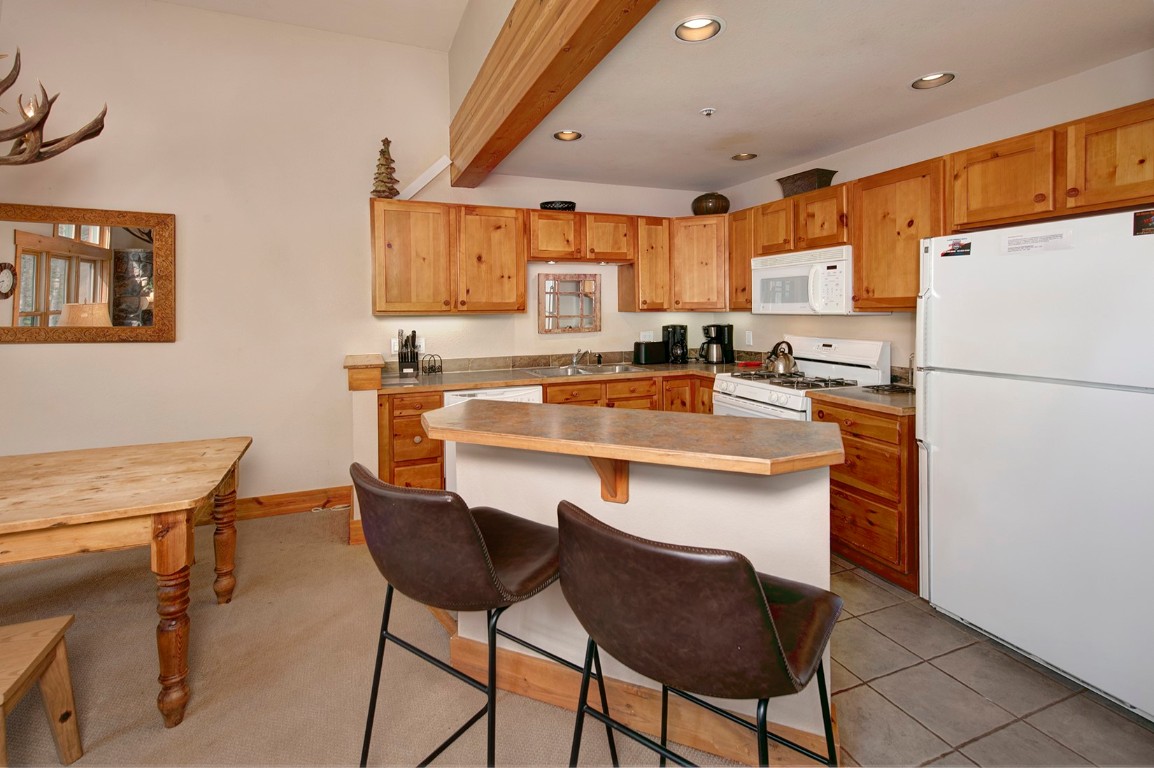 28 Trappers Crossing Trail, Unit 8760 Keystone, CO 80435 - Photo 16 of 37 a kitchen with a dining table chairs refrigerator and cabinets