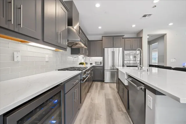 a kitchen with stainless steel appliances granite countertop a sink a stove and a refrigerator