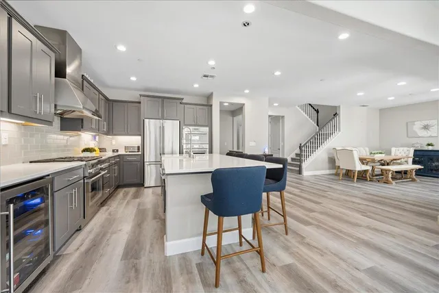 a kitchen with stainless steel appliances kitchen island granite countertop a stove a sink a refrigerator and chairs