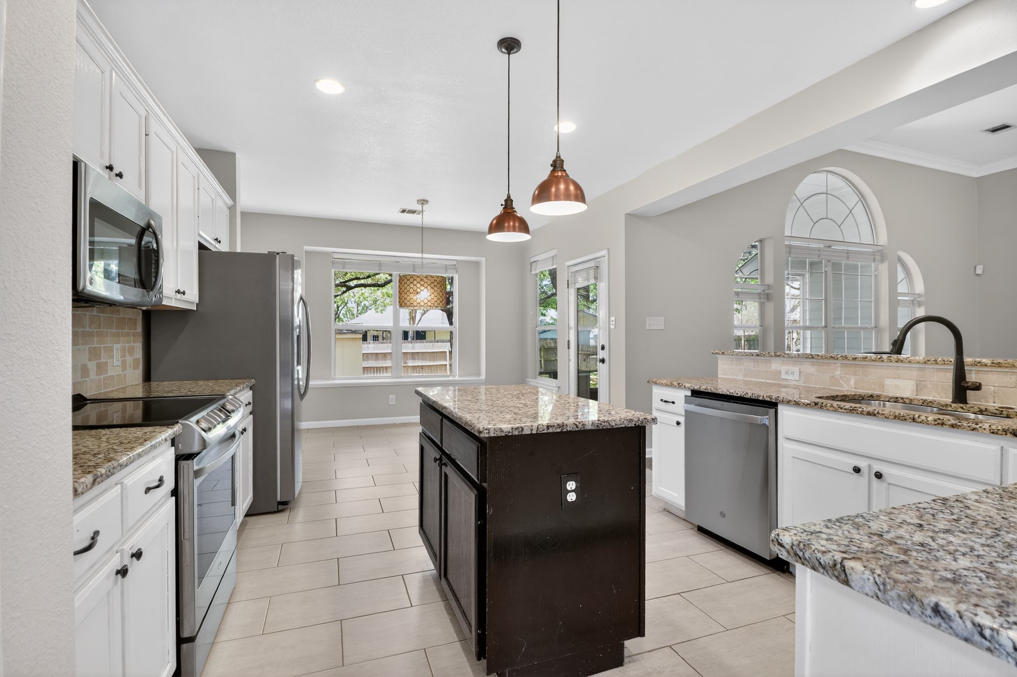 11918 Arbor Downs Road Austin, TX 78748 - Photo 12 of 29 Dual tone kitchen with stainless steel appliances, backsplash, a center island, hanging light fixtures, and light stone countertops