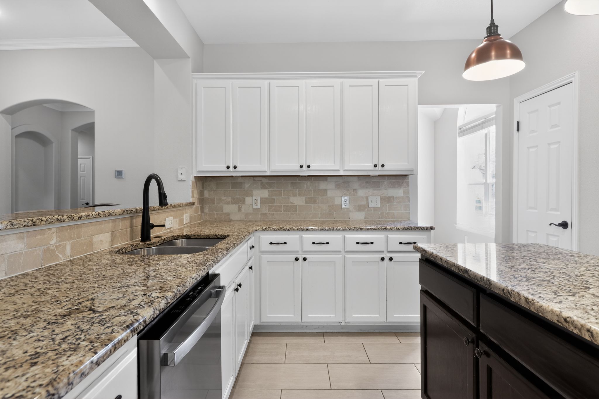 11918 Arbor Downs Road Austin, TX 78748 - Photo 15 of 29 Two tone kitchen featuring two tone cabinets, light stone counters, stainless steel dishwasher, pendant lighting, and decorative backsplash