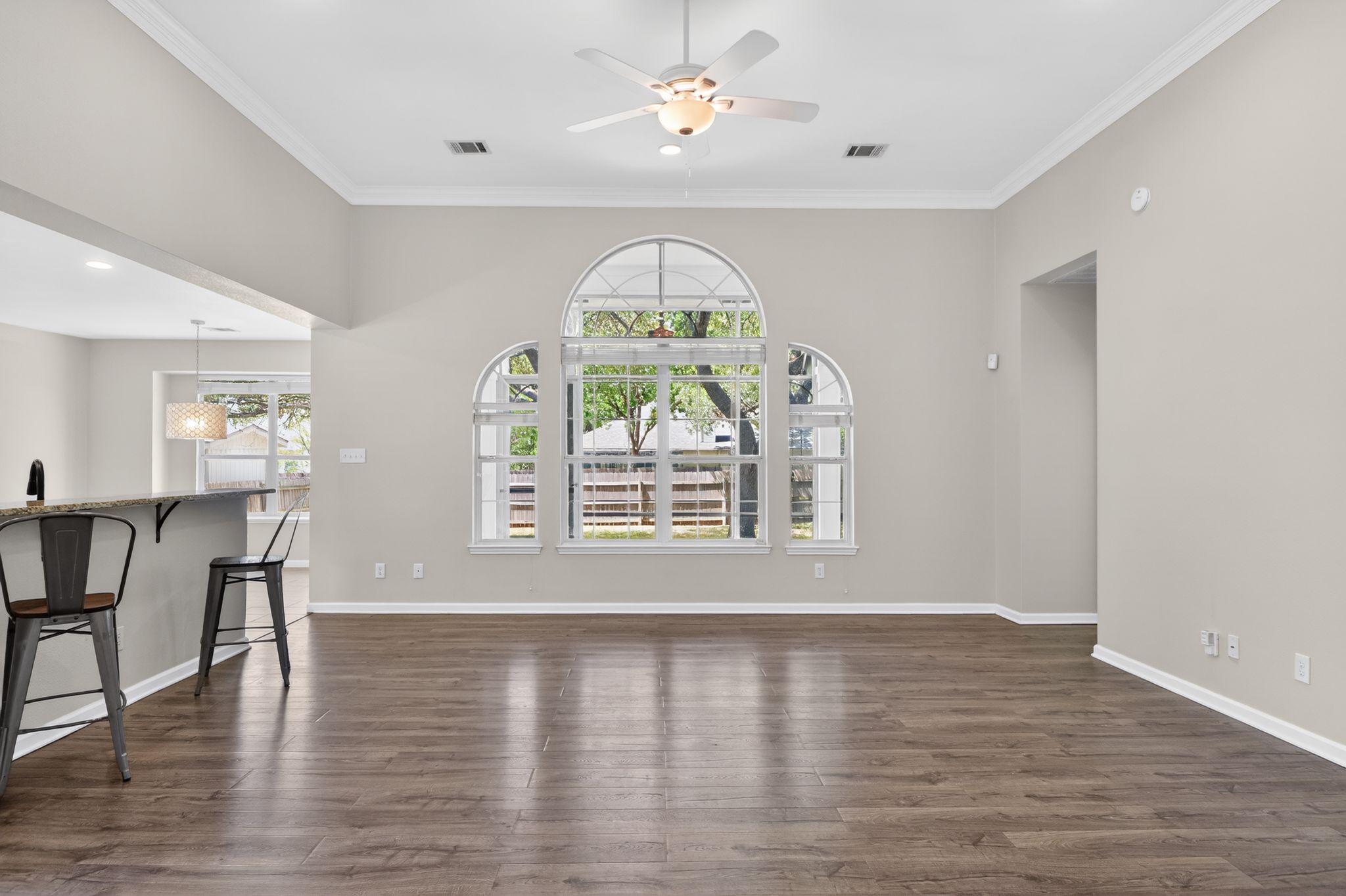 11918 Arbor Downs Road Austin, TX 78748 - Photo 7 of 29 open living room with dark wood-style flooring, a ceiling fan, and crown molding