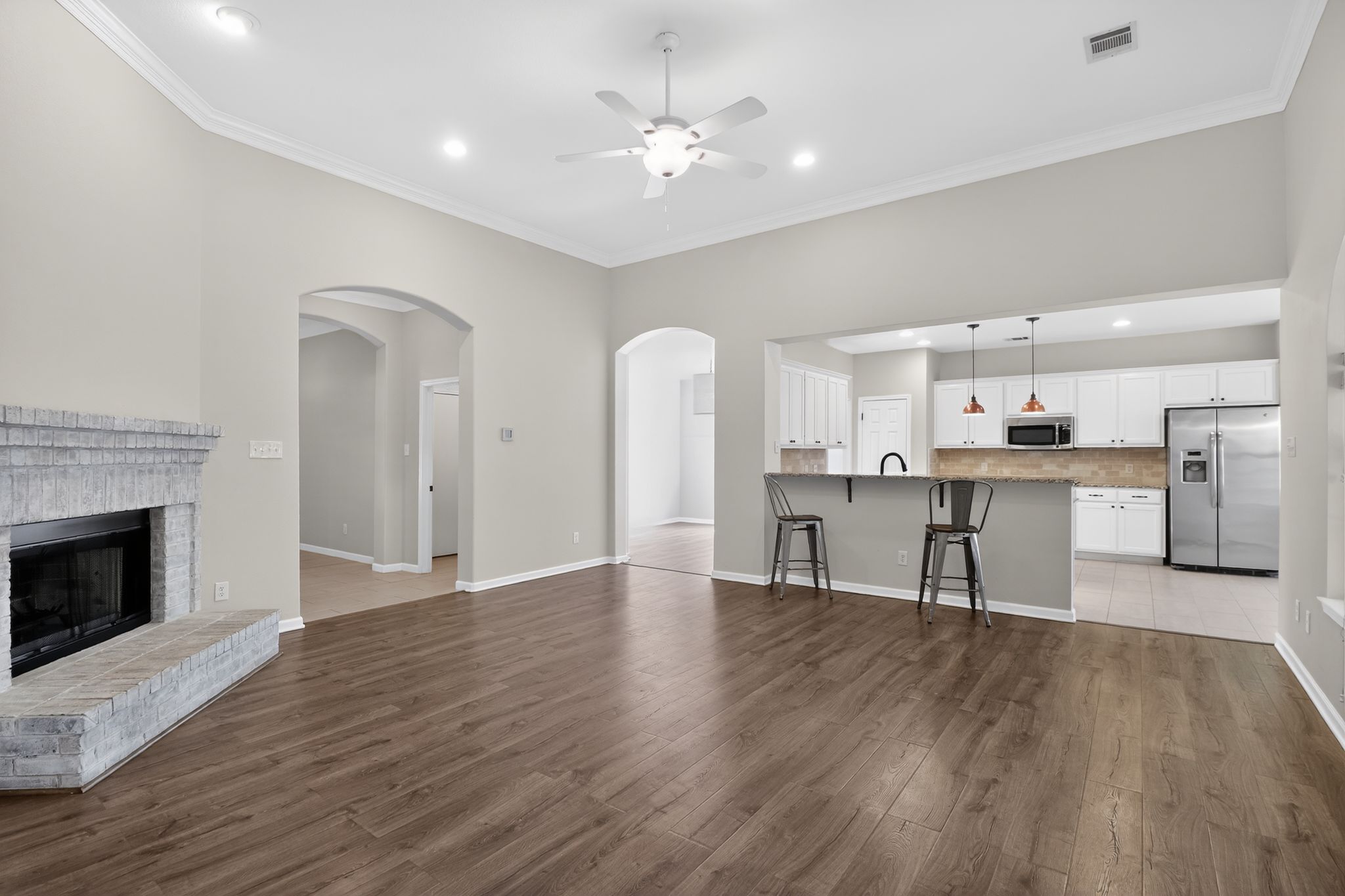 11918 Arbor Downs Road Austin, TX 78748 - Photo 8 of 29 open living room featuring a ceiling fan, a brick fireplace, dark wood-type flooring, ornamental molding, and recessed lighting