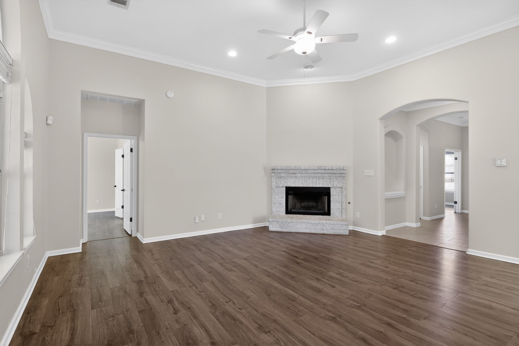 11918 Arbor Downs Road Austin, TX 78748 - Photo 9 of 29 open living room with crown molding, ceiling fan, dark wood-style floors, a brick fireplace, and recessed lighting