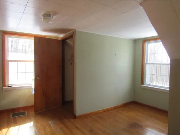 an empty room with wooden floor and windows