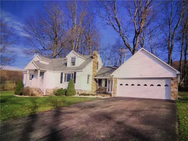 a view of a white house with a big yard and large trees