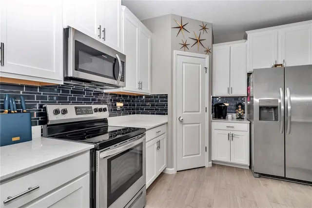 a kitchen with cabinets stainless steel appliances and wooden floor