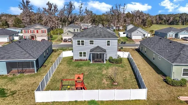 a view of a house with a small yard and large tree