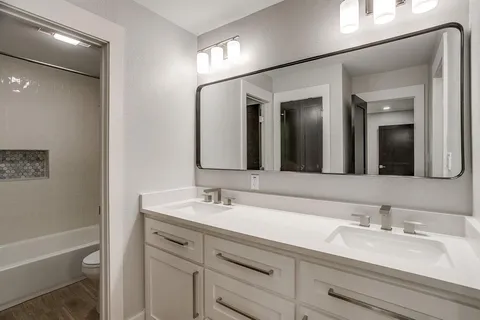 a bathroom with a sink double vanity granite tub and a mirror