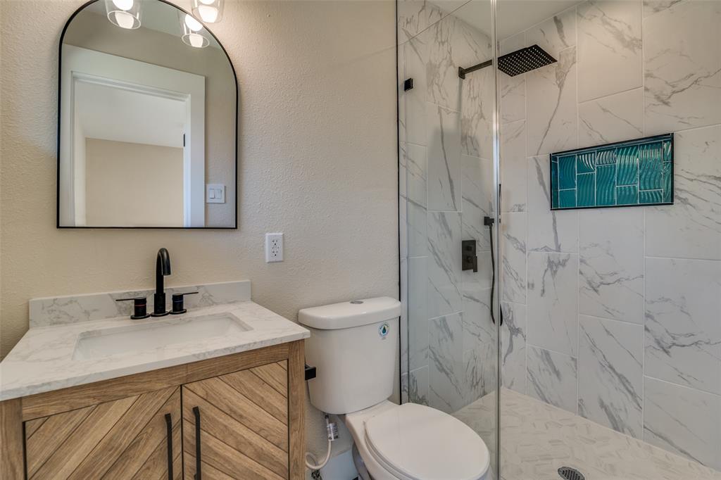 9209 Rustown Drive Dallas, TX 75228 - Photo 16 of 28 a bathroom with a toilet sink vanity and mirror