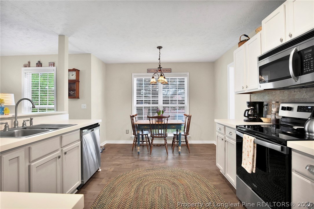 4425 Bishamon Street Hope Mills, NC 28348 - Photo 13 of 39 a kitchen with stainless steel appliances granite countertop a stove top oven a sink dishwasher and white cabinets with wooden floor