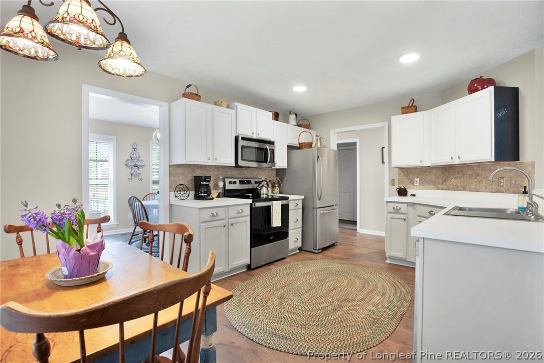 4425 Bishamon Street Hope Mills, NC 28348 - Photo 16 of 39 a kitchen with stainless steel appliances kitchen island granite countertop a sink a stove a refrigerator cabinets and a dining table