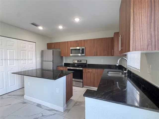 a kitchen with granite countertop a refrigerator sink and stove