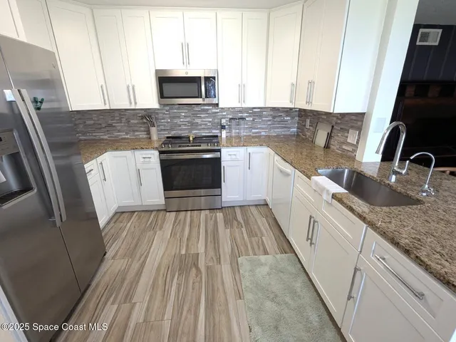 a kitchen with granite countertop a sink stove and cabinets