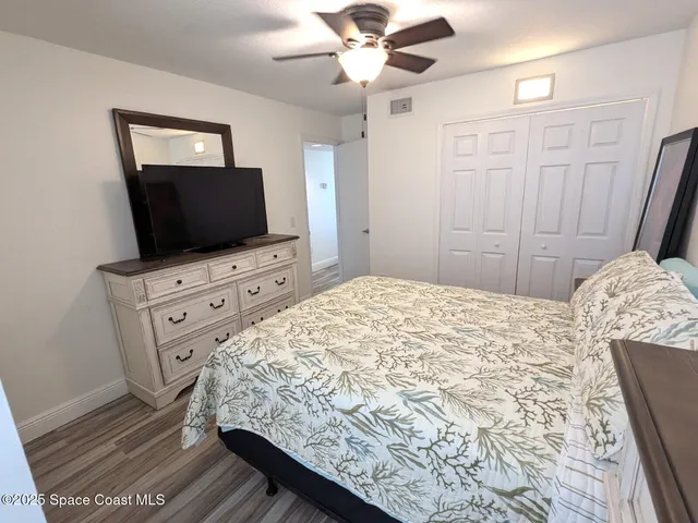 a bedroom with a bed and a flat tv screen on dresser