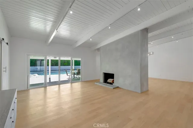 an empty room with wooden floor fireplace and windows