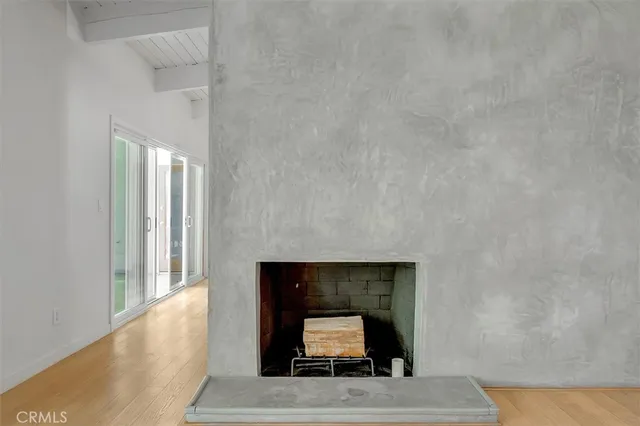 a view of an empty room with wooden floor and a fireplace