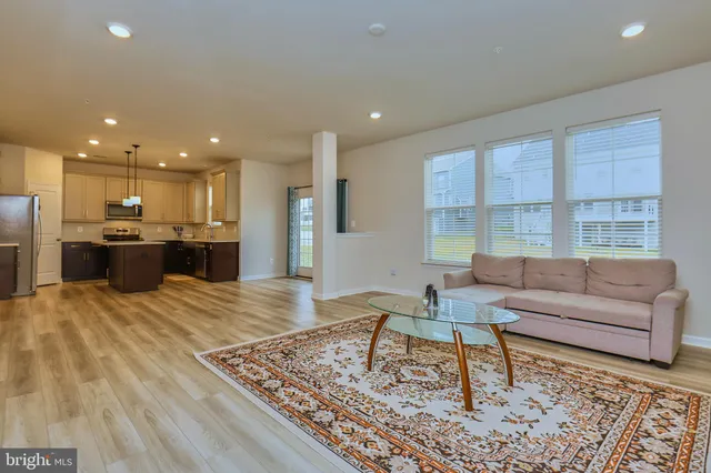 a kitchen with kitchen island granite countertop a stove top oven a sink dishwasher a refrigerator white cabinets and wooden floor