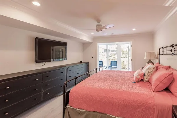 a bedroom with a large bed and a flat tv screen on dresser