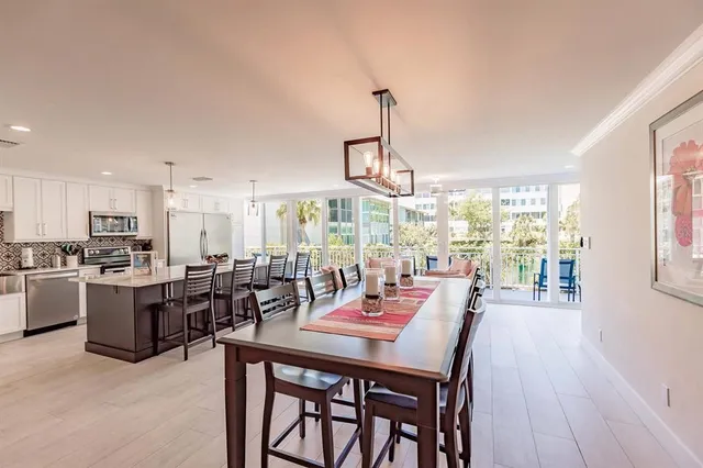 a view of a dining room and livingroom with furniture wooden floor a rug a flat screen tv a rug and a painting