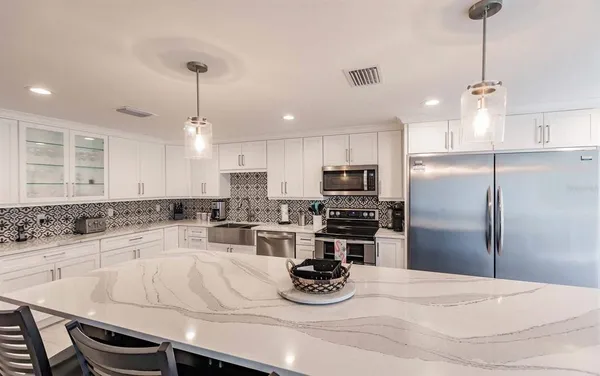 a kitchen with a refrigerator a stove a sink and white cabinets