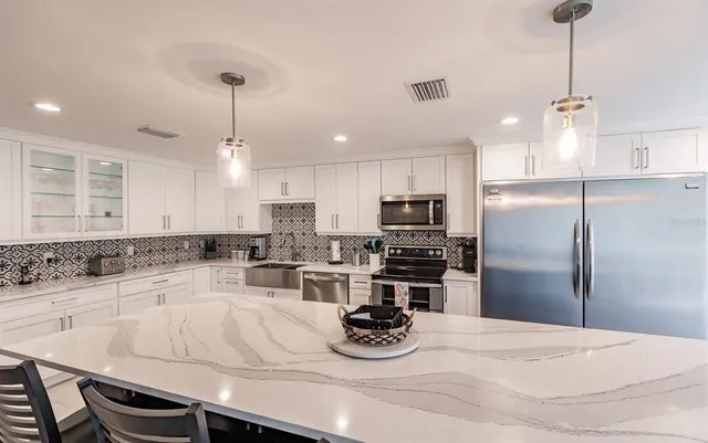 a kitchen with a refrigerator a stove a sink and white cabinets