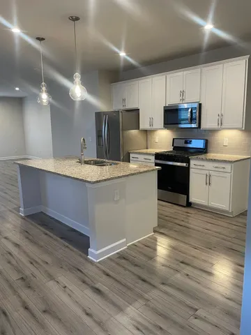 a kitchen with stainless steel appliances granite countertop a sink a stove and a wooden floors