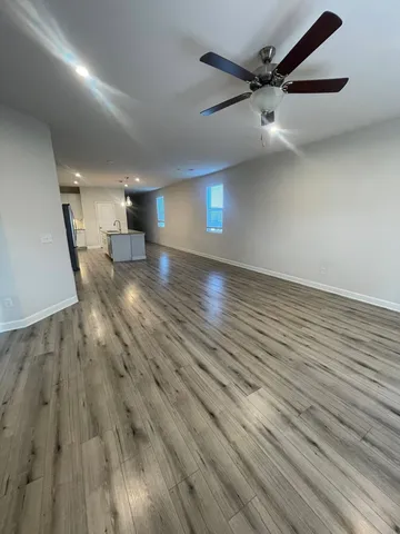 an empty room with wooden floor and a ceiling fan