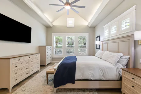 a bedroom with a large bed and a flat tv screen on dresser