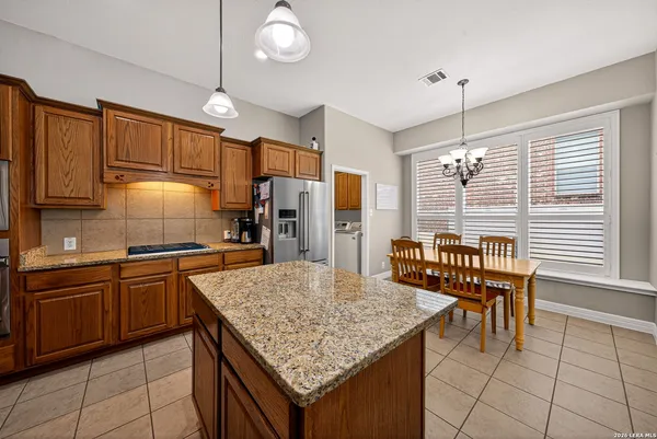 a kitchen with granite countertop kitchen island stainless steel appliances a table chairs sink and cabinets