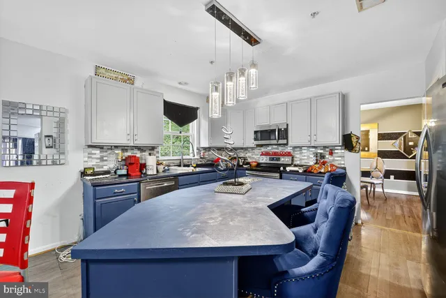 a kitchen with kitchen island granite countertop a stove sink cabinets and wooden floor