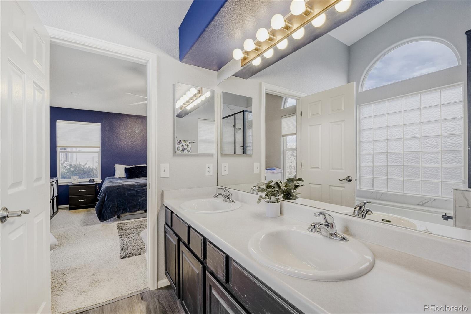 7085 Leopard Gate Lone Tree, CO 80124 - Photo 13 of 26 a en suite bathroom with a double vanity sink a mirror and a shower