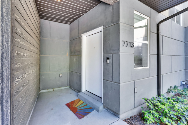 7713 Navarro View Court Midvale, UT 84047 - Photo 5 of 41 Modern entryway featuring a white door, contrasting gray siding, and a vertical window