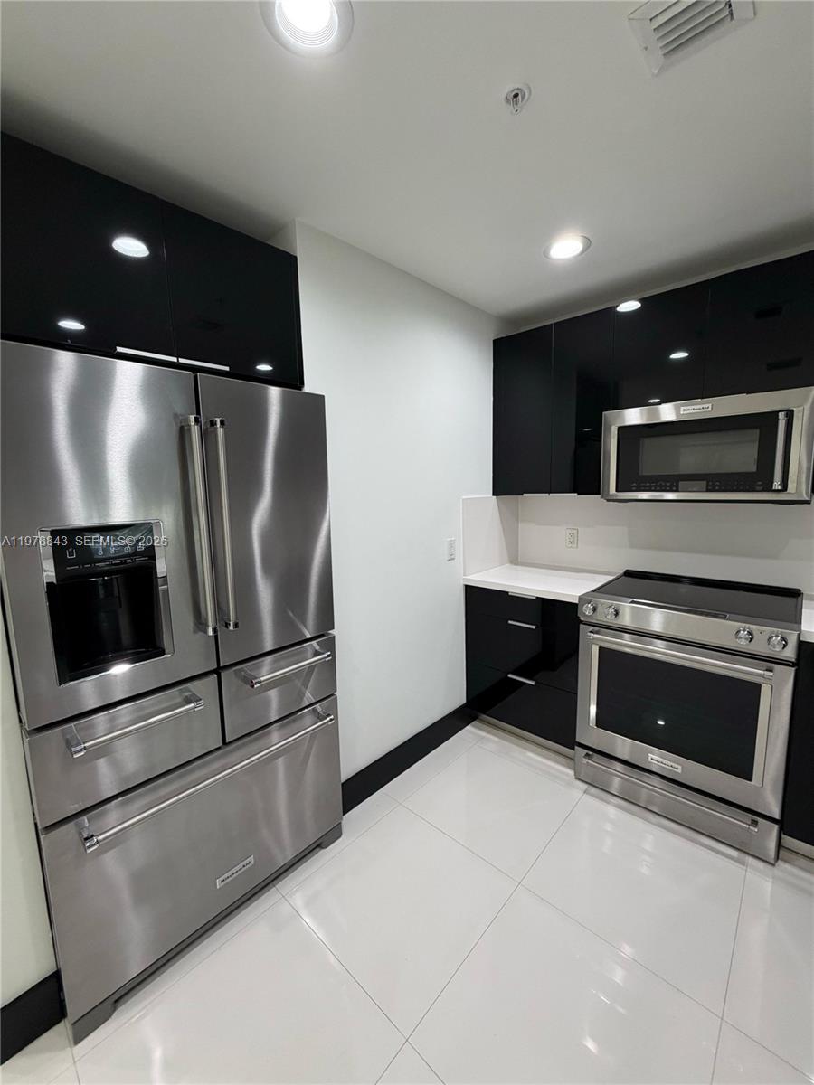 2699 Tigertail Avenue, Unit 14 Miami, FL 33133 - Photo 9 of 28 a kitchen with stainless steel appliances kitchen island granite countertop a stove and a refrigerator