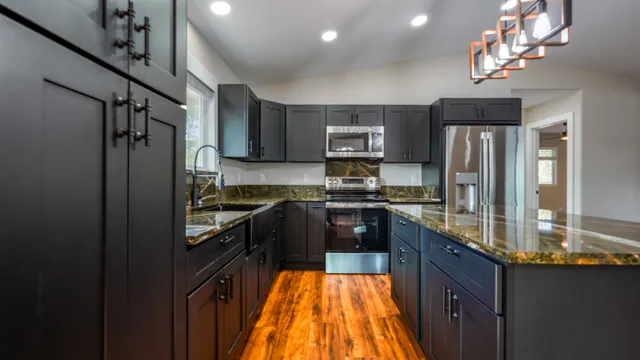 a kitchen with kitchen island granite countertop stainless steel appliances a sink stove refrigerator and cabinets