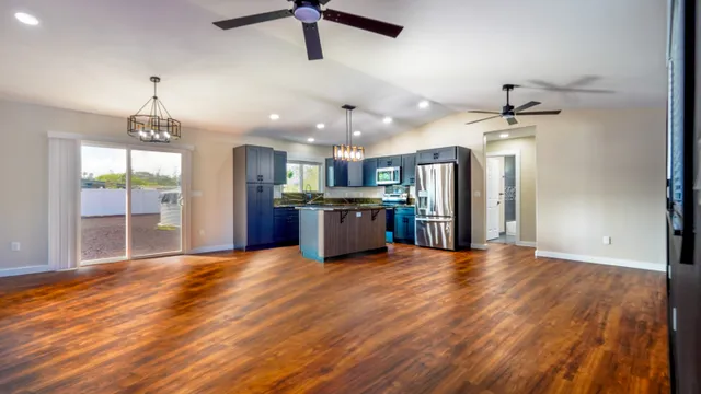 a view of an empty room with kitchen and a window