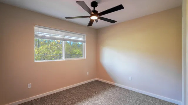 an empty room with a window and a fan