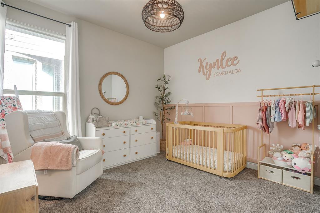 5821 Rendyn Court Midlothian, TX 76065 - Photo 24 of 30 a bedroom with a baby bed a chandelier and a dresser