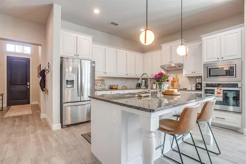 a kitchen with stainless steel appliances granite countertop a kitchen island a stove a cabinets a sink and a white cabinets