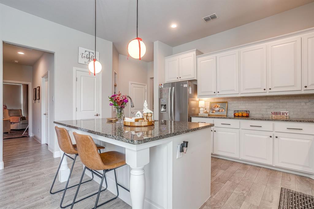 5821 Rendyn Court Midlothian, TX 76065 - Photo 7 of 30 a kitchen with stainless steel appliances kitchen island granite countertop a table chairs in it and wooden floors