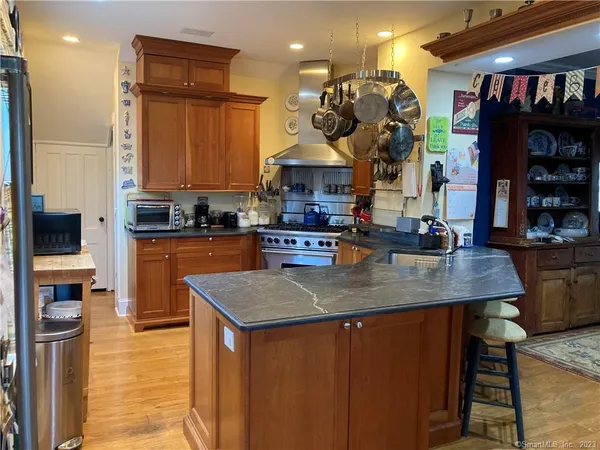 a kitchen with stainless steel appliances granite countertop a sink a stove and a wooden cabinets