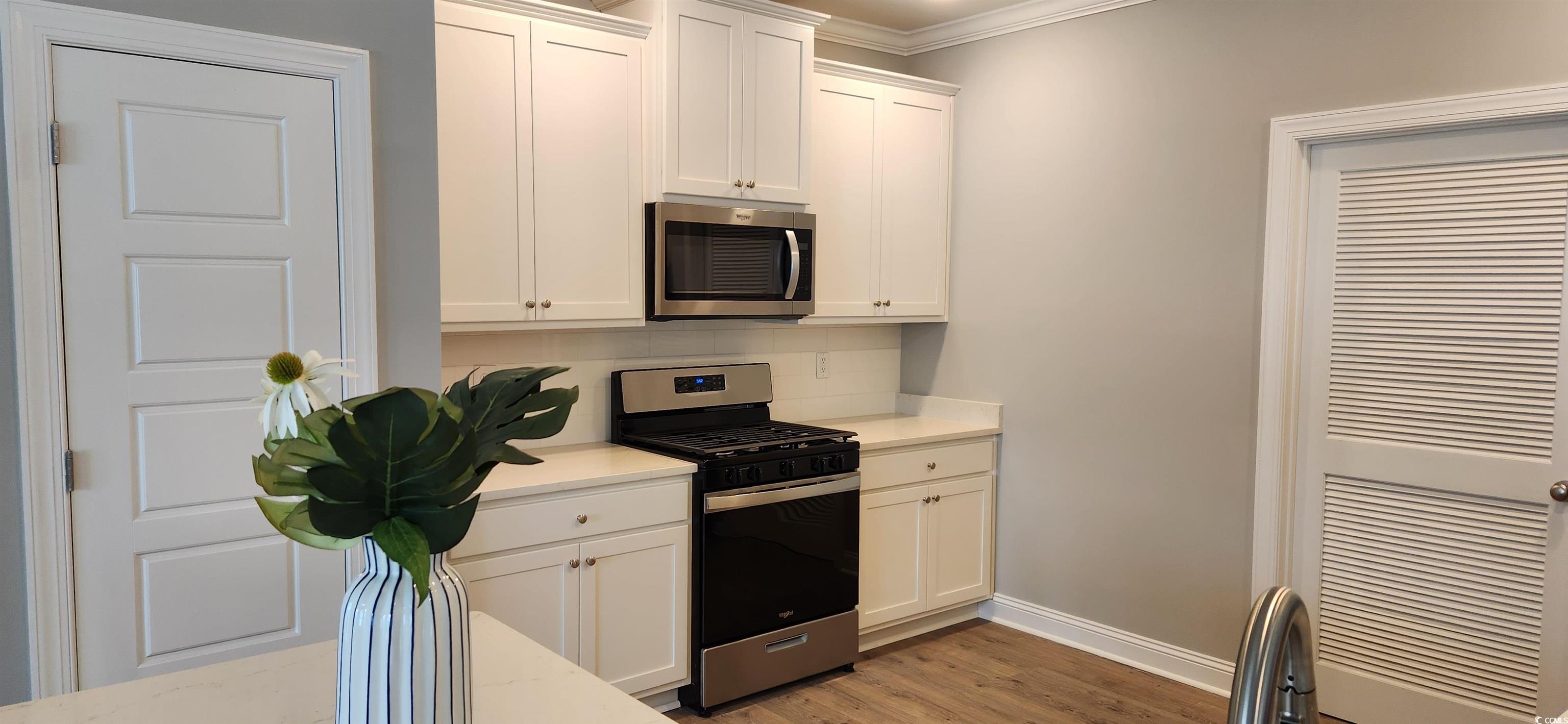 1407 Gooseneck Place, Unit 102 Murrells Inlet, SC 29576 - Photo 10 of 39 Kitchen featuring white cabinetry, light hardwood