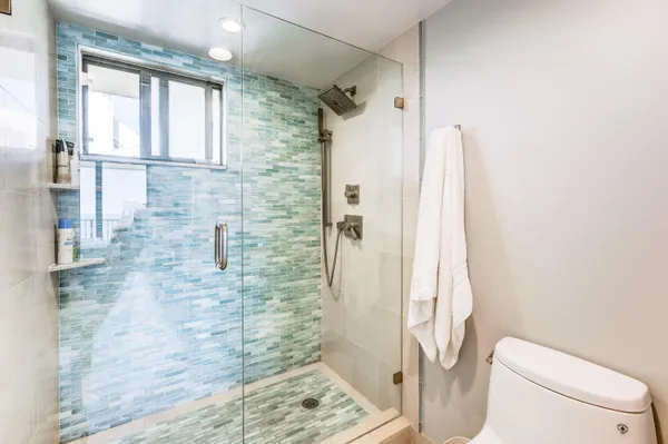 a bathroom with a granite countertop shower a toilet and a shower