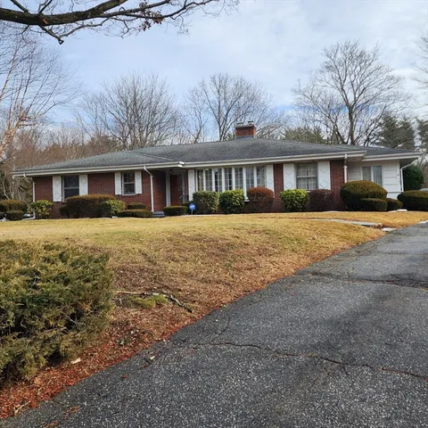 a front view of a house with a yard and trees