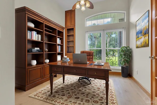 an empty room with wooden floor fan and windows